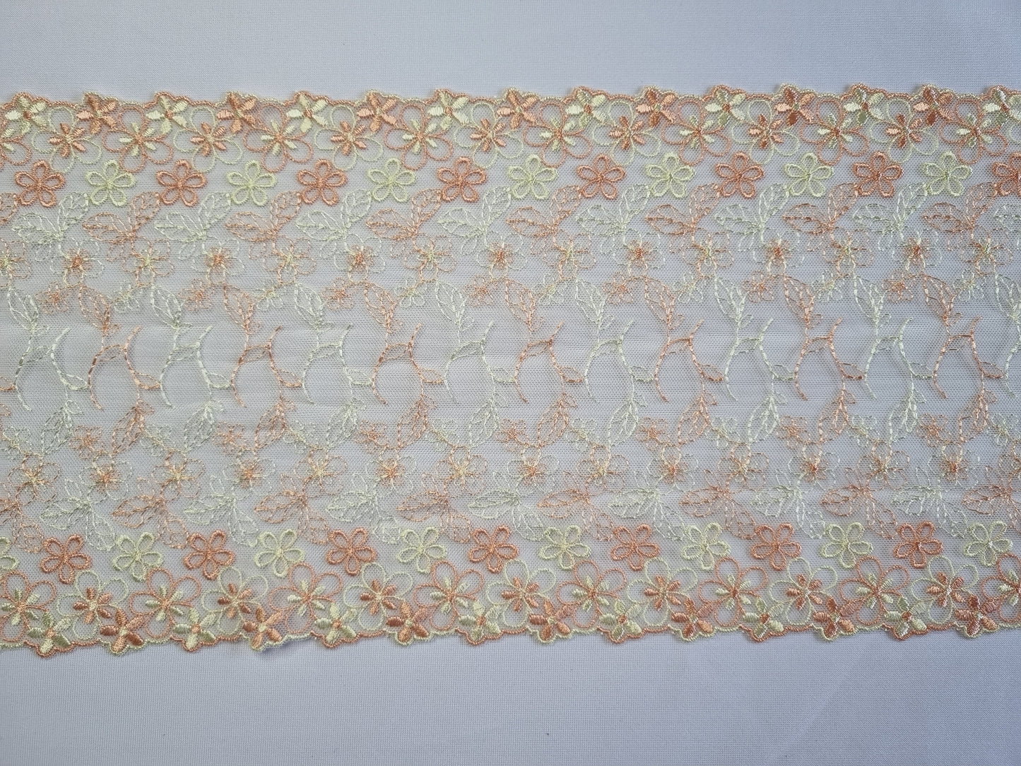 Vrolijk wit tule kant met pastel gele en oranje bloesem