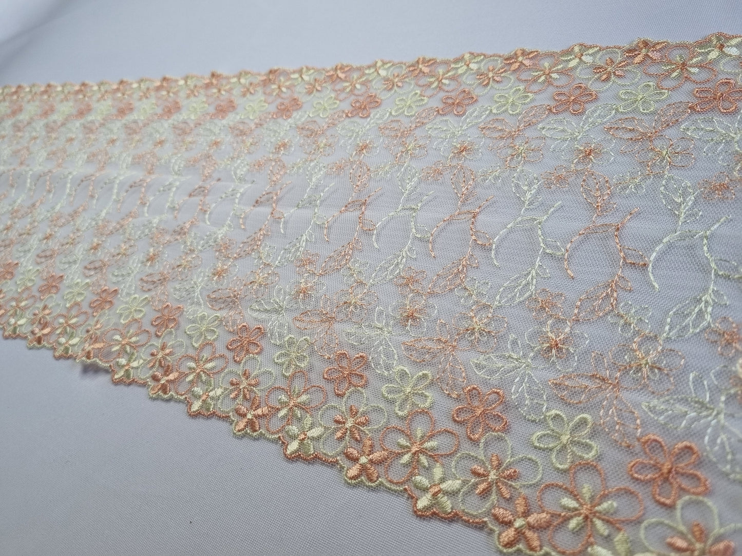 Vrolijk wit tule kant met pastel gele en oranje bloesem