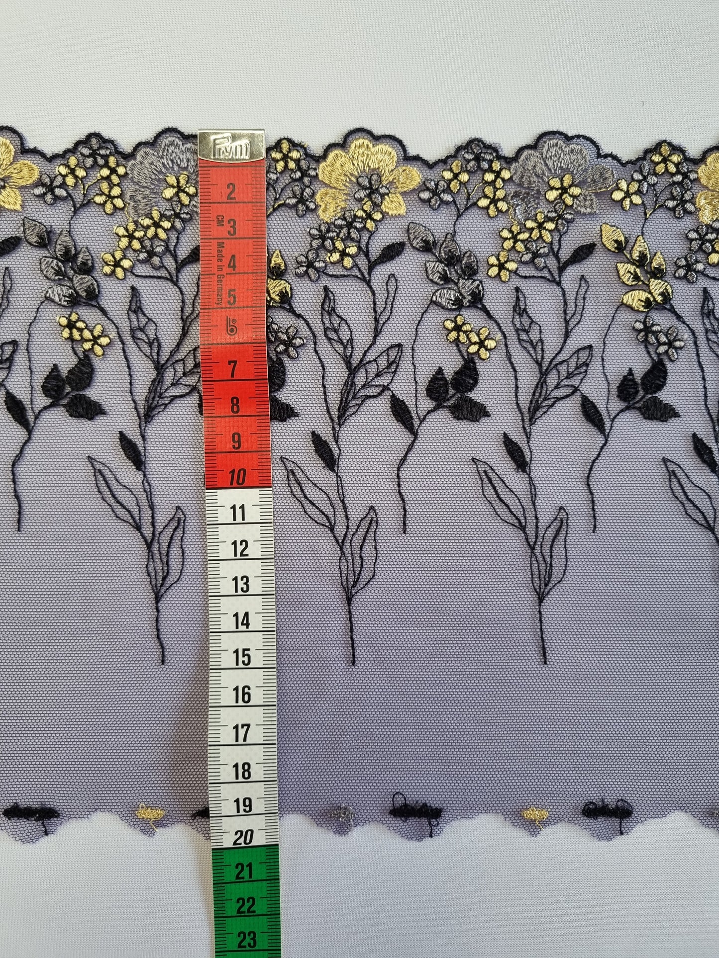 Donkerblauw tule kant met gele en blauwe genorduurde bloemetjes