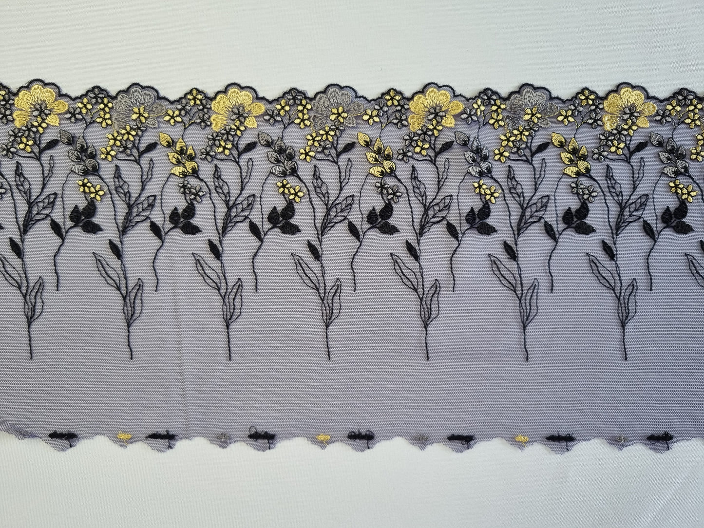 Donkerblauw tule kant met gele en blauwe genorduurde bloemetjes