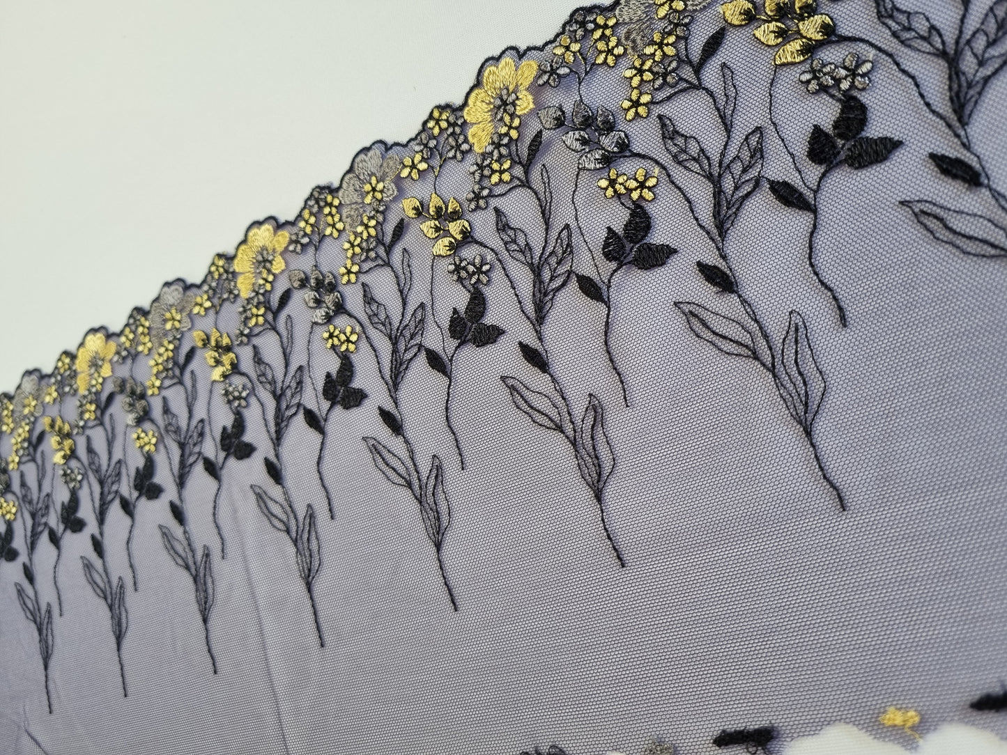 Donkerblauw tule kant met gele en blauwe genorduurde bloemetjes