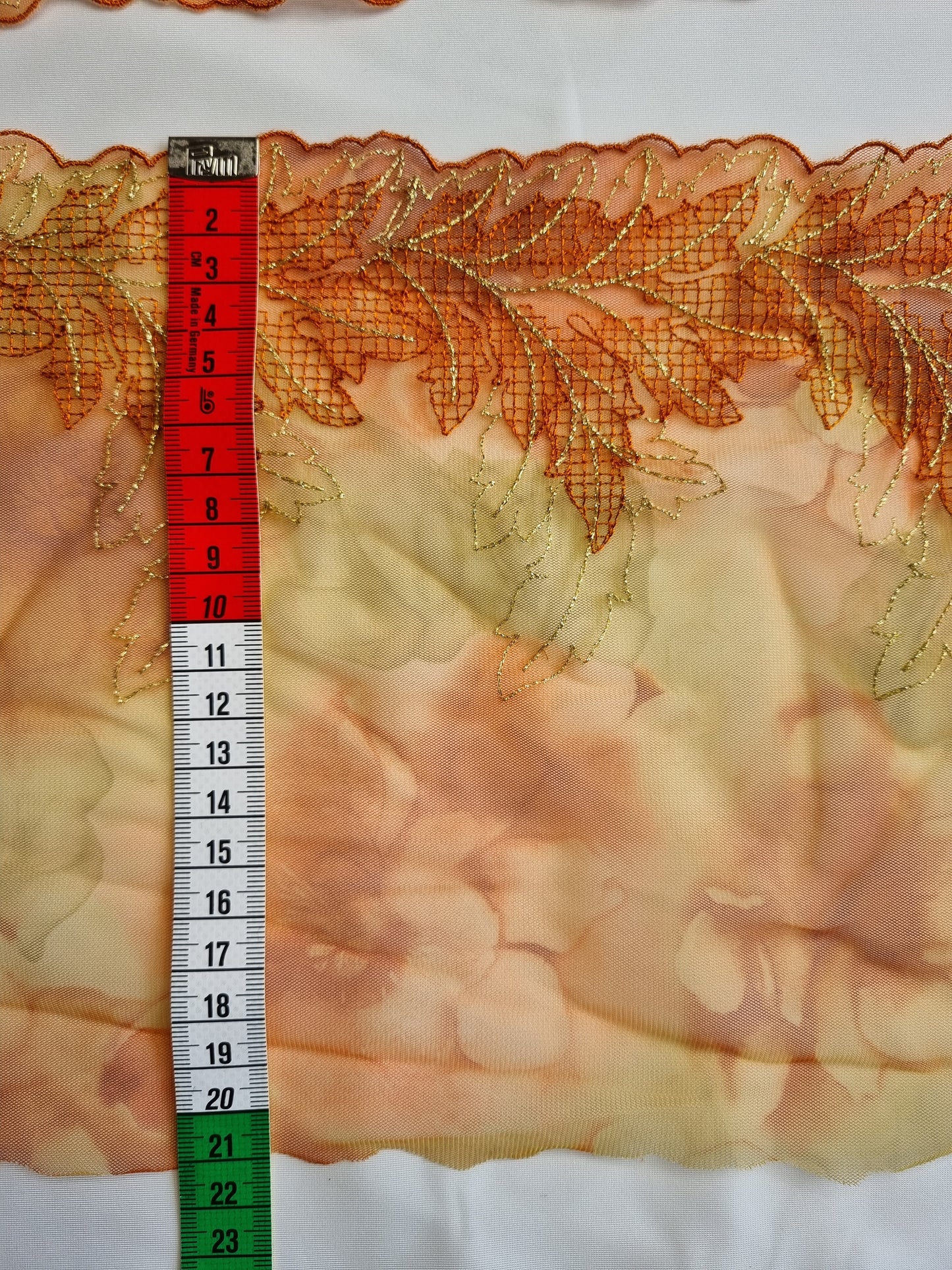 Oranje tule kant met geborduurde abstracte blaadjes.