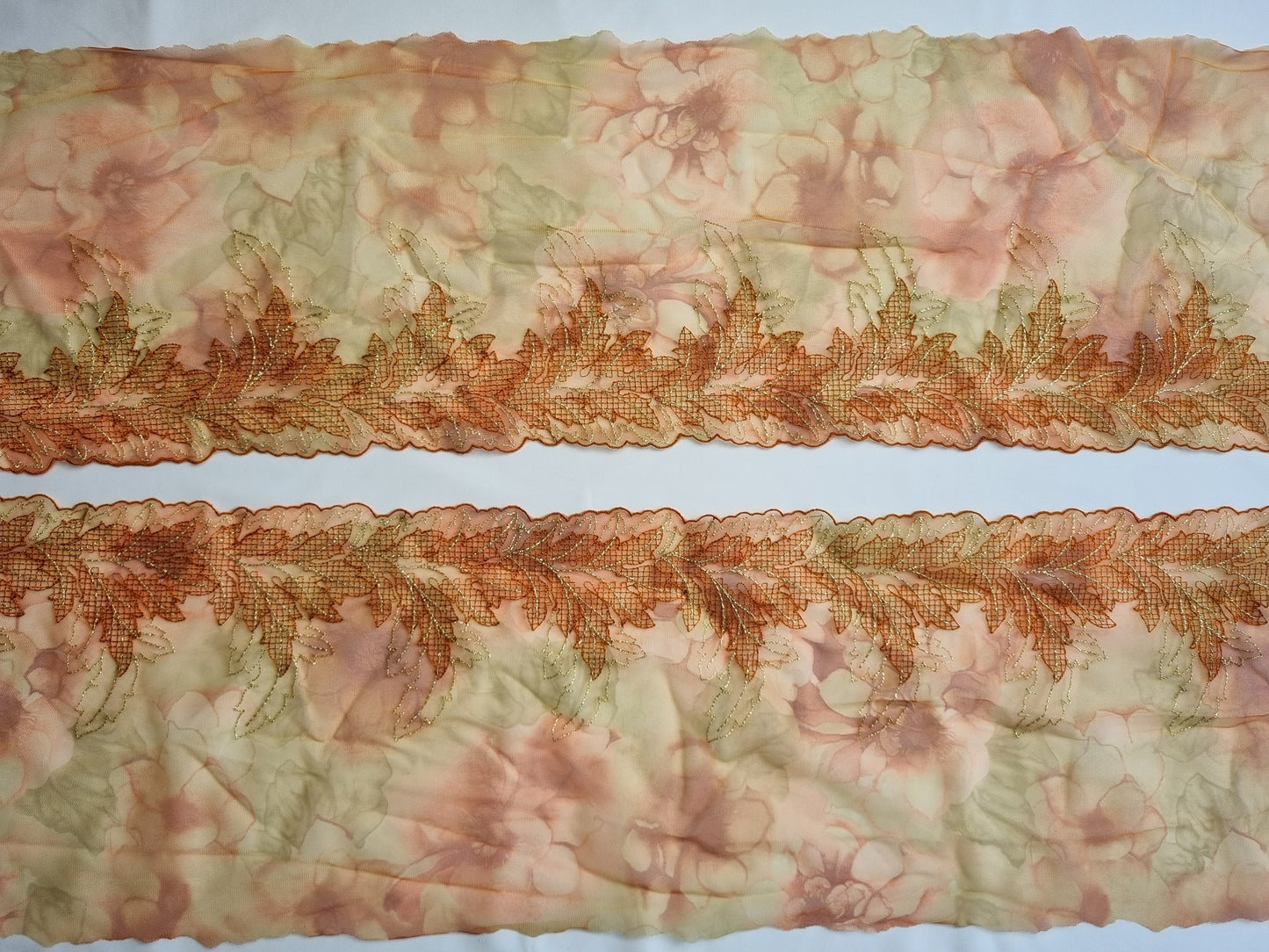 Oranje tule kant met geborduurde abstracte blaadjes.