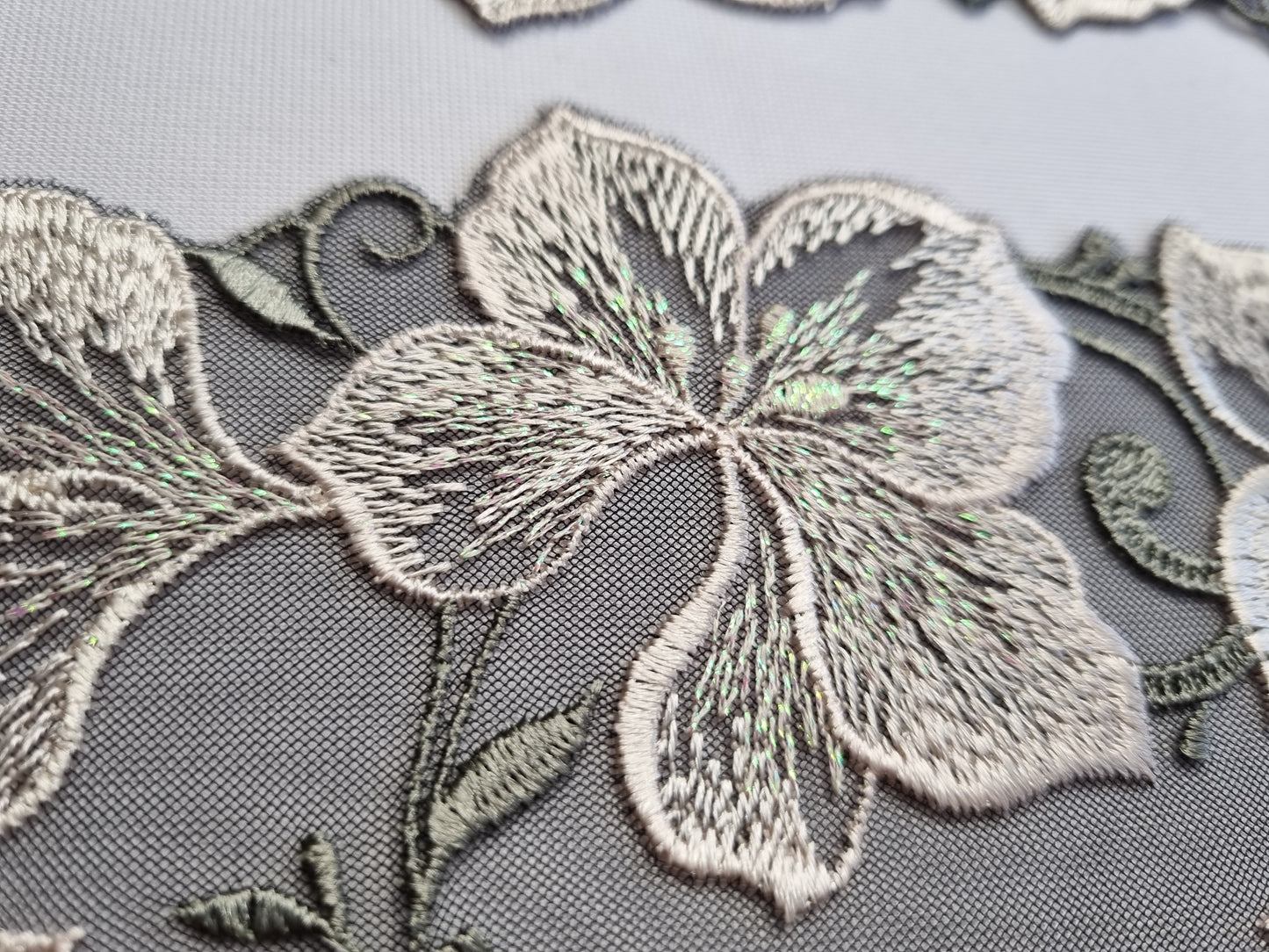 Bijzonder antraciet tule kant met iriserende parelgrijze bloemen