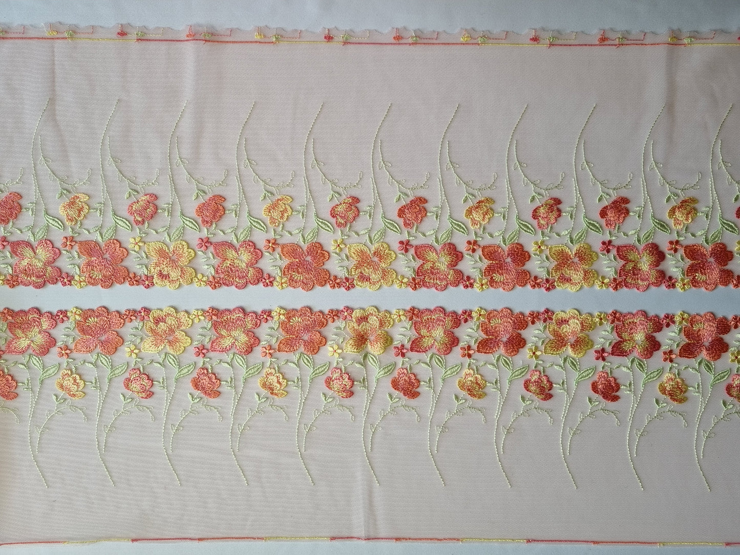 Peach kleurig tule kant met peach en zacht geel geborduurde roosjes