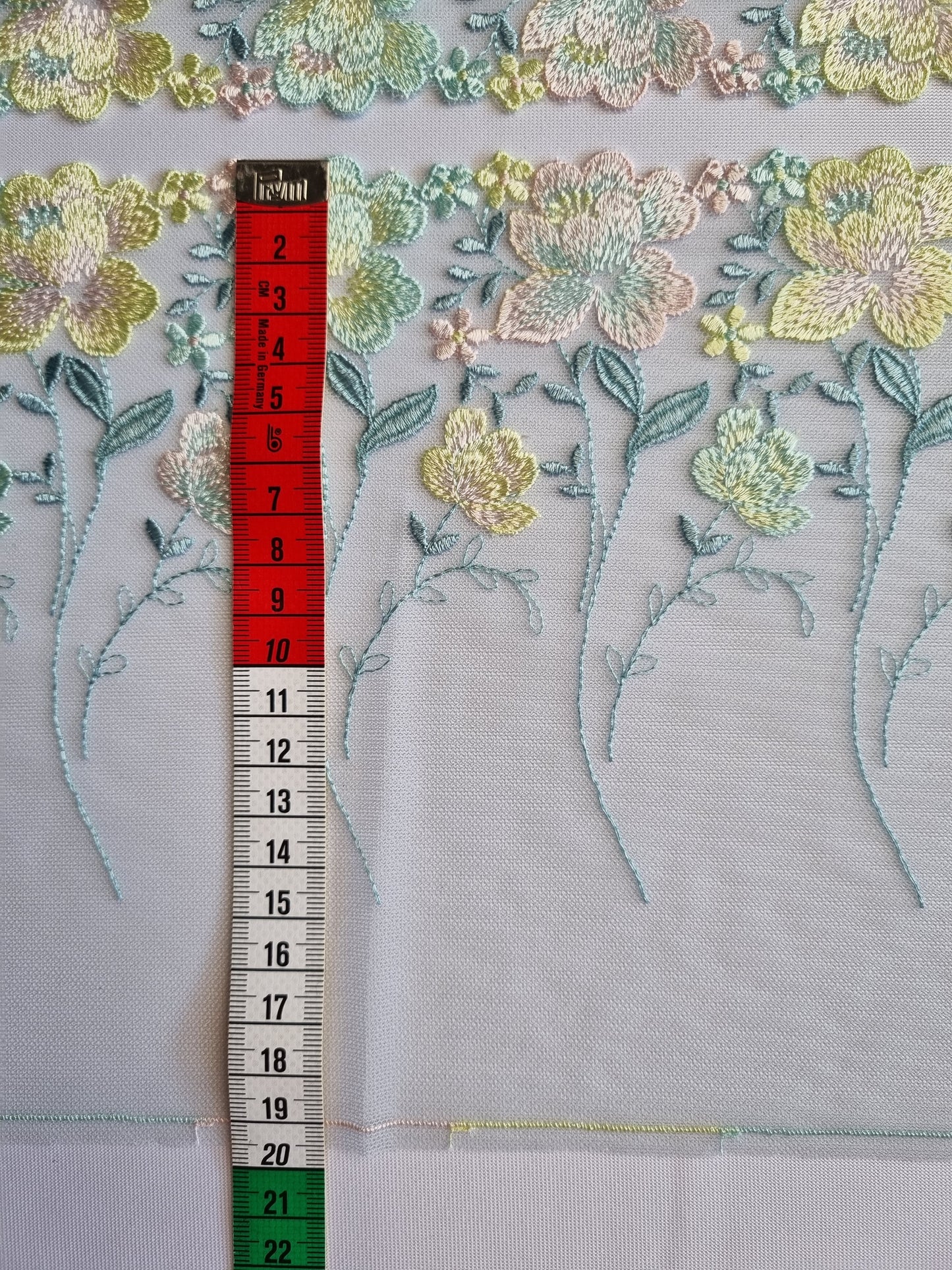 Mint kleurig tule kant met licht roze, mint en zacht geel geborduurde roosjes