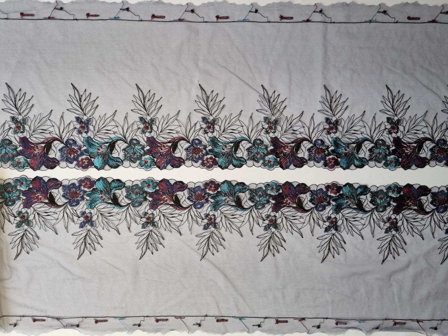 Zwart tule kant met geborduurde lelies in aubergine en turquoise
