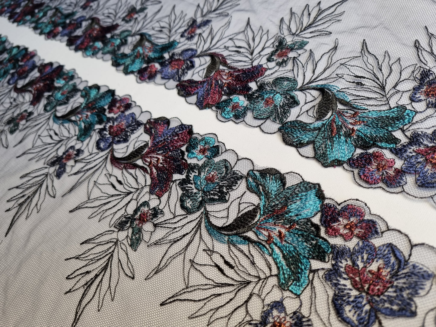 Zwart tule kant met geborduurde lelies in aubergine en turquoise