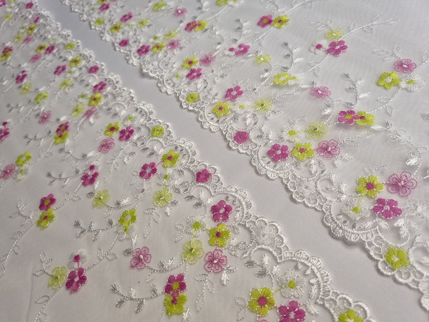 Wit tule kant met kleine geborduurde bloemetjes in wit, fuchsia en lime.