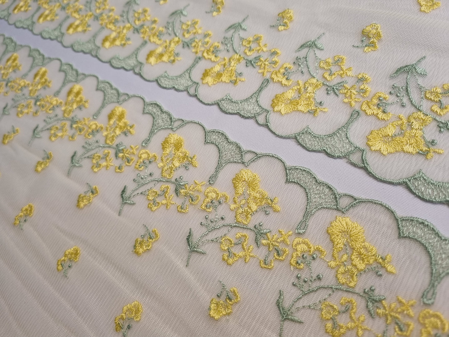 Licht geel tule kant met licht geel geborduurde, kleine bloemetjes