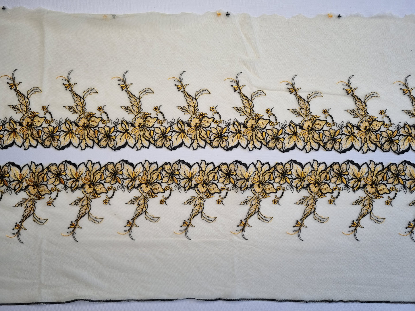 Geel tule kant met zwart en geel geborduurde lelies