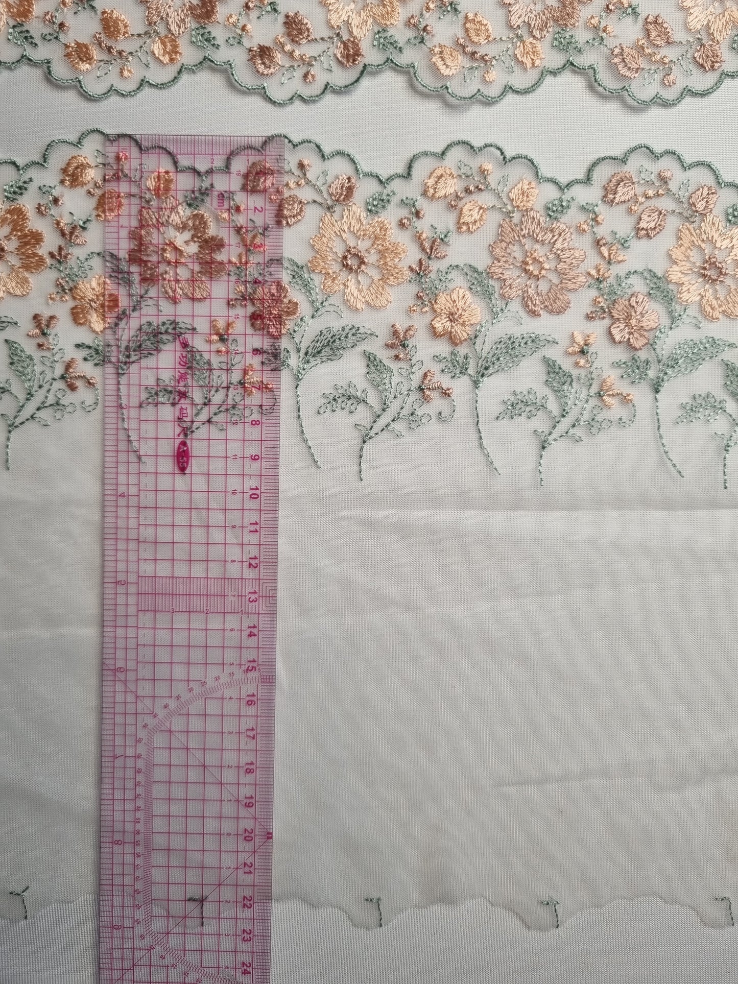 Wit tule kant met geborduurde bloemen in oudroze