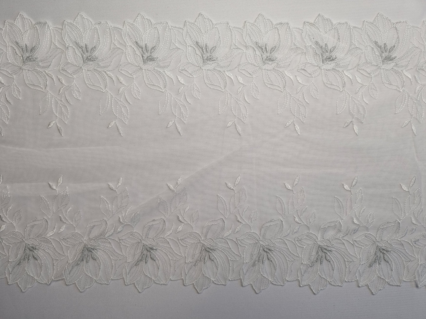 Wit tule kant met wit geborduurde lelies en zilverkleurig hartje van lurex draad