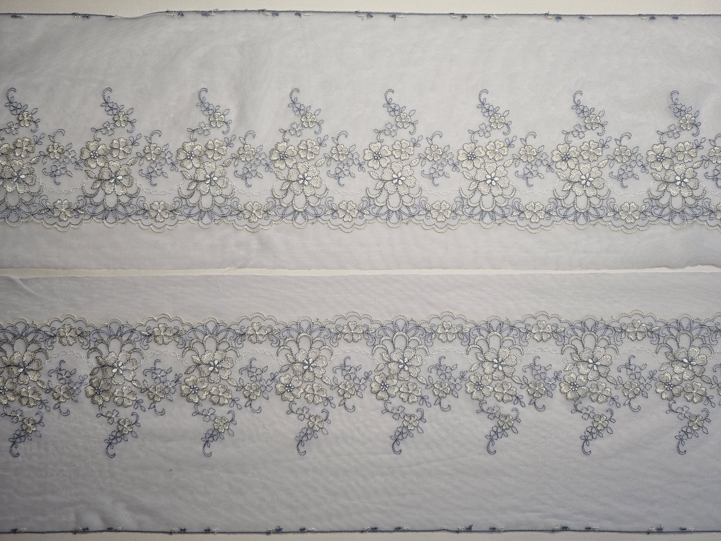 Lavedelblauw tule kant met wit en lavendel geborduurde bloemen