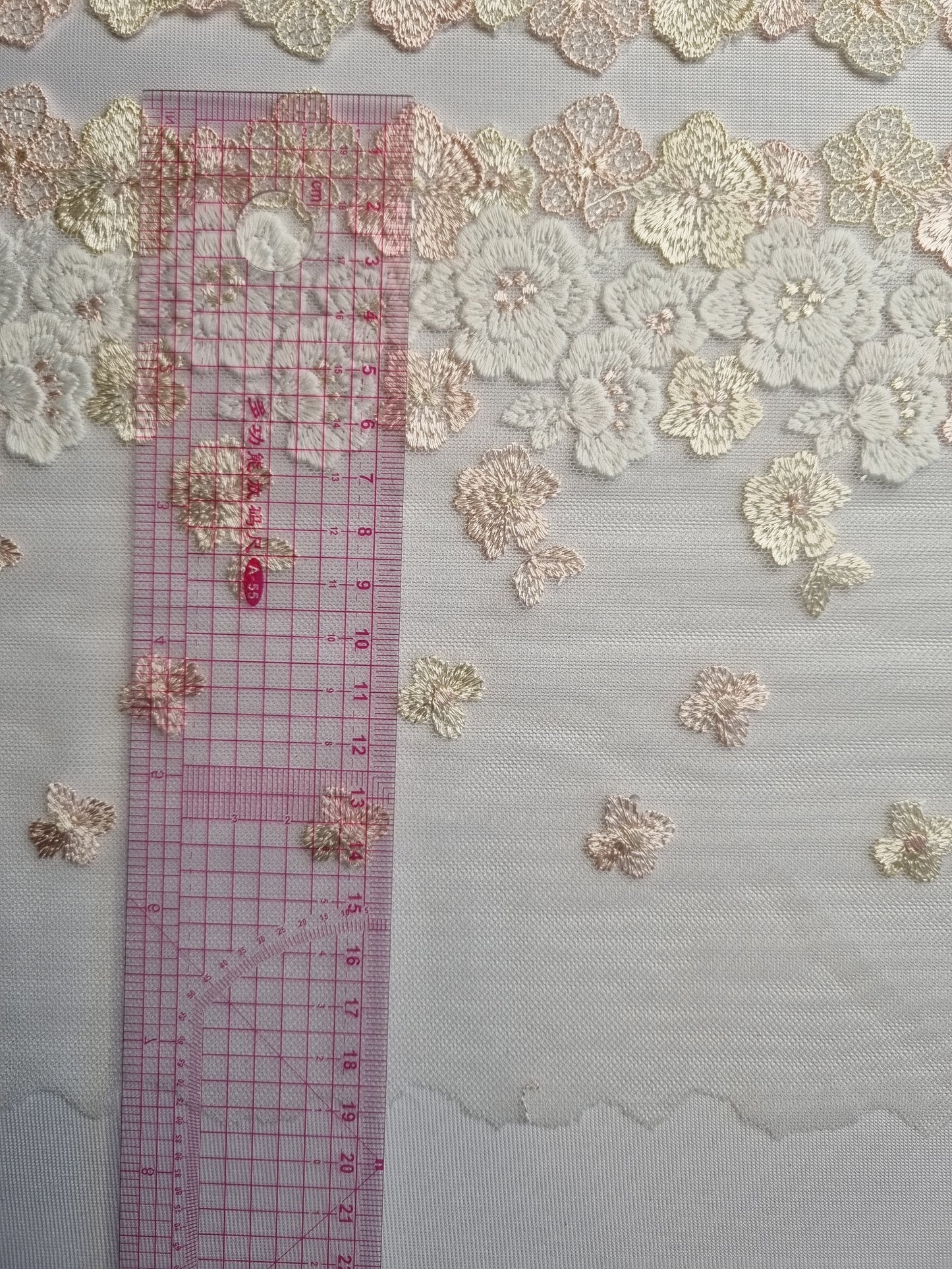 Wit tule kant met geborduurde bloemen in wit, roze en beige kleuren