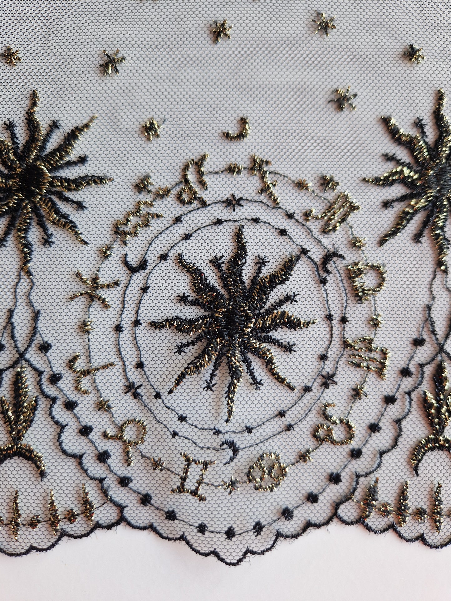 2024-115 Zwart tule kant met astrologisch borduursel met goudkleurig lurexdraad.