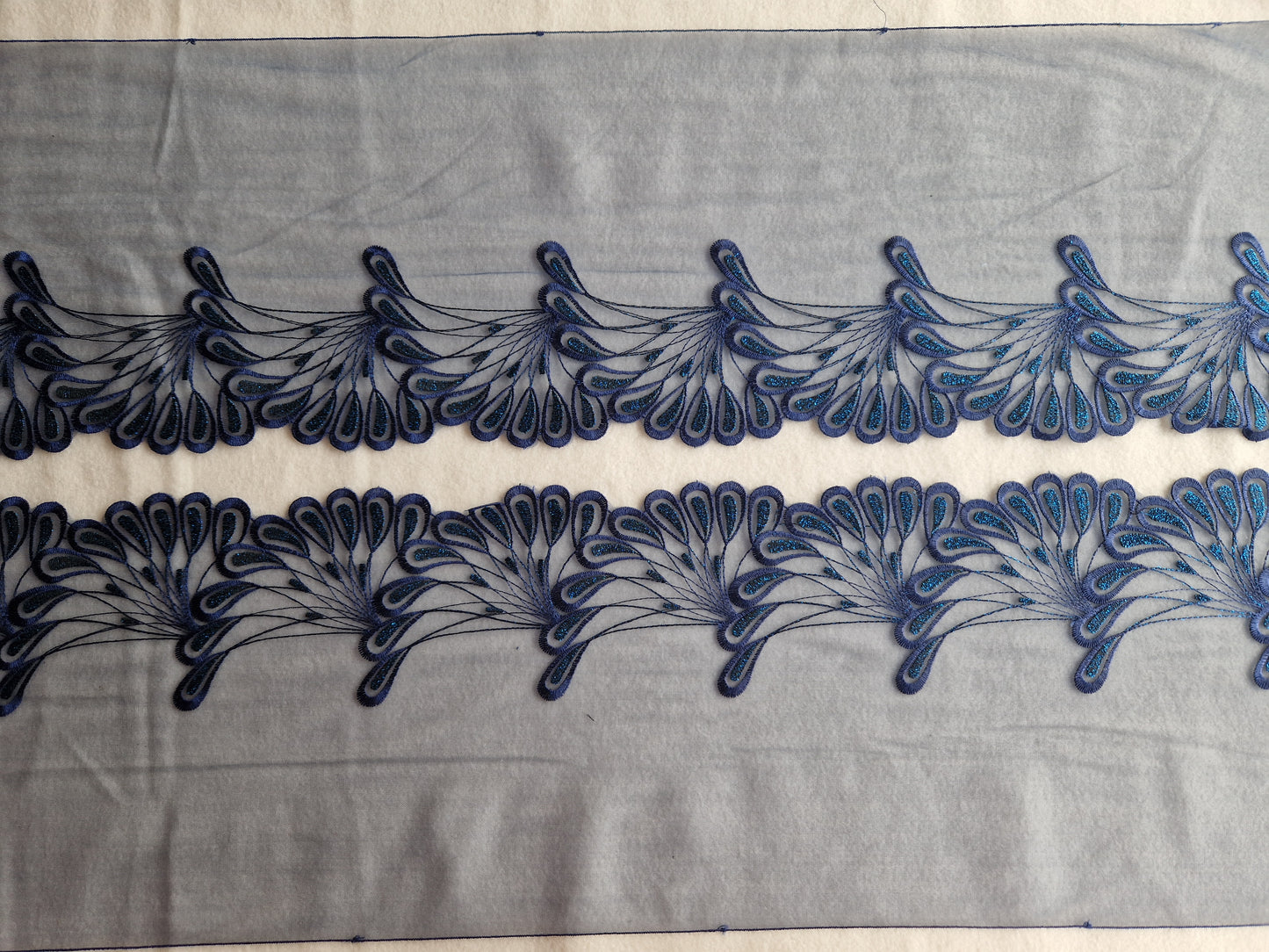 2024-133 Donker blauw tule kant met abstracte pauwenveren met blauw lurex draadje.