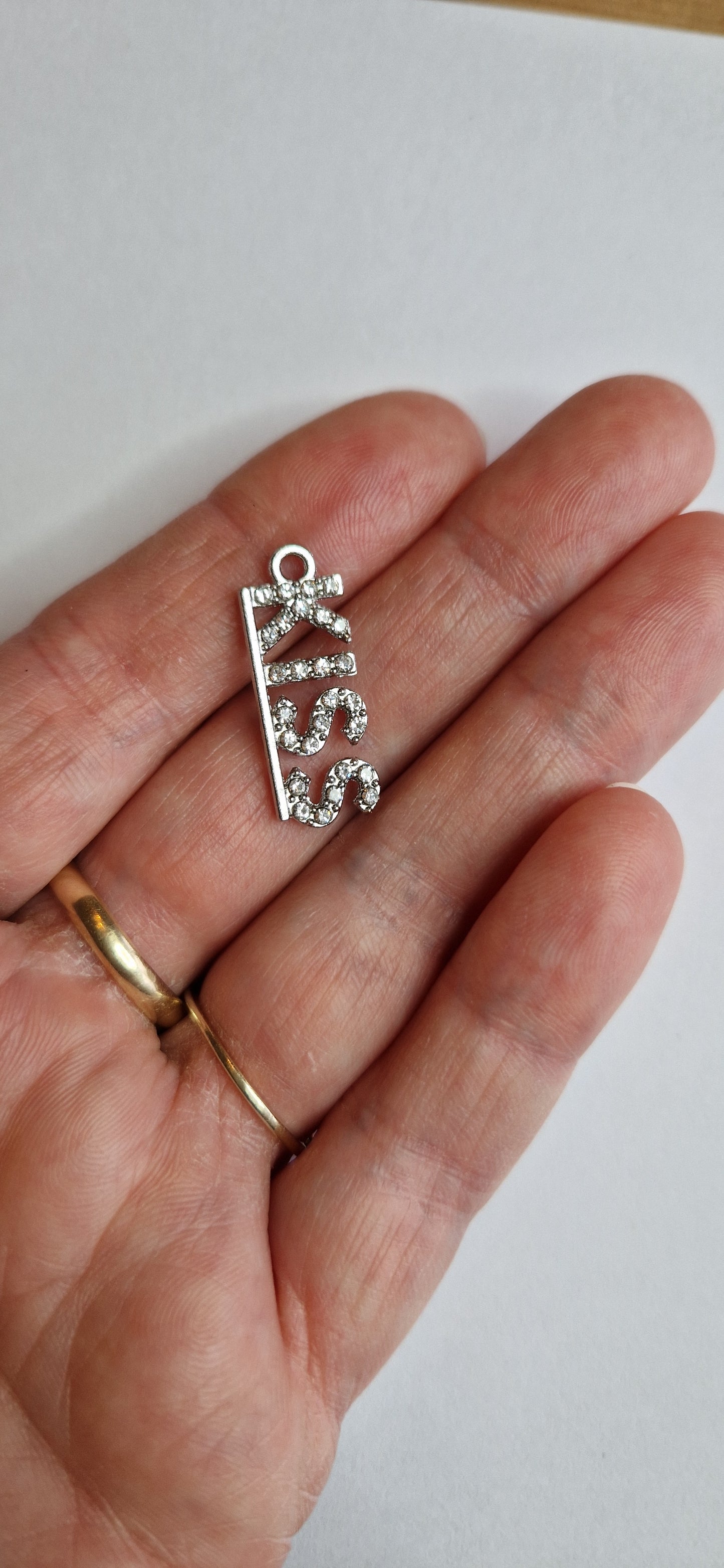 Zilver kleurig bedeltje met "KISS" in zirconiatjes