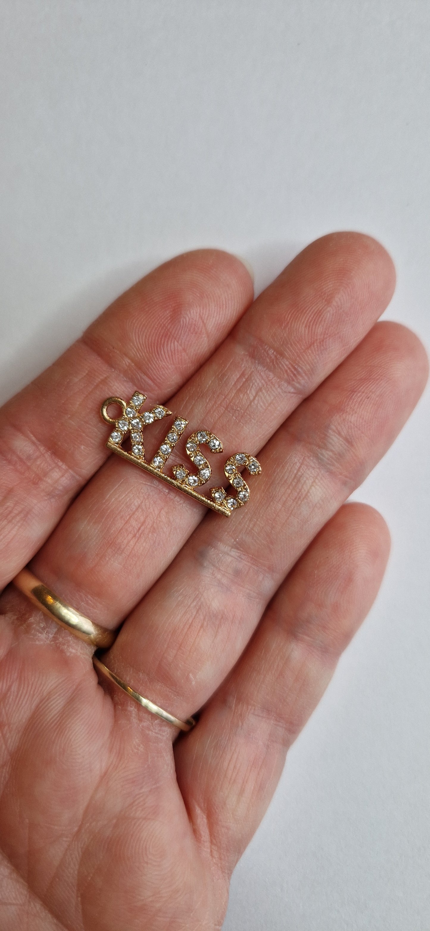 goud kleurig bedeltje met "KISS" in zirconiatjes