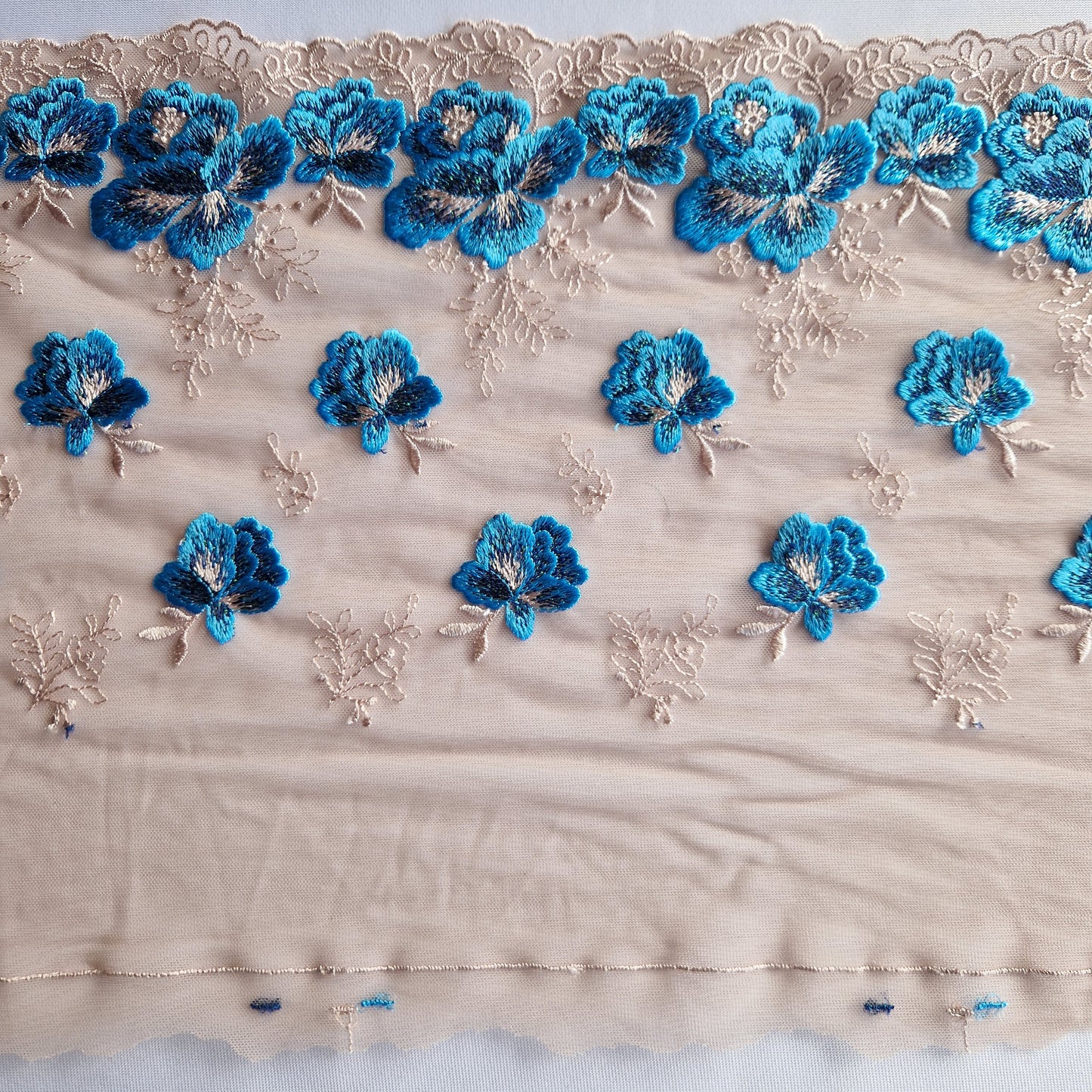 2025-21 beige tule stretchkant met blauwe roosjes voorzien van iriserend lurex draad