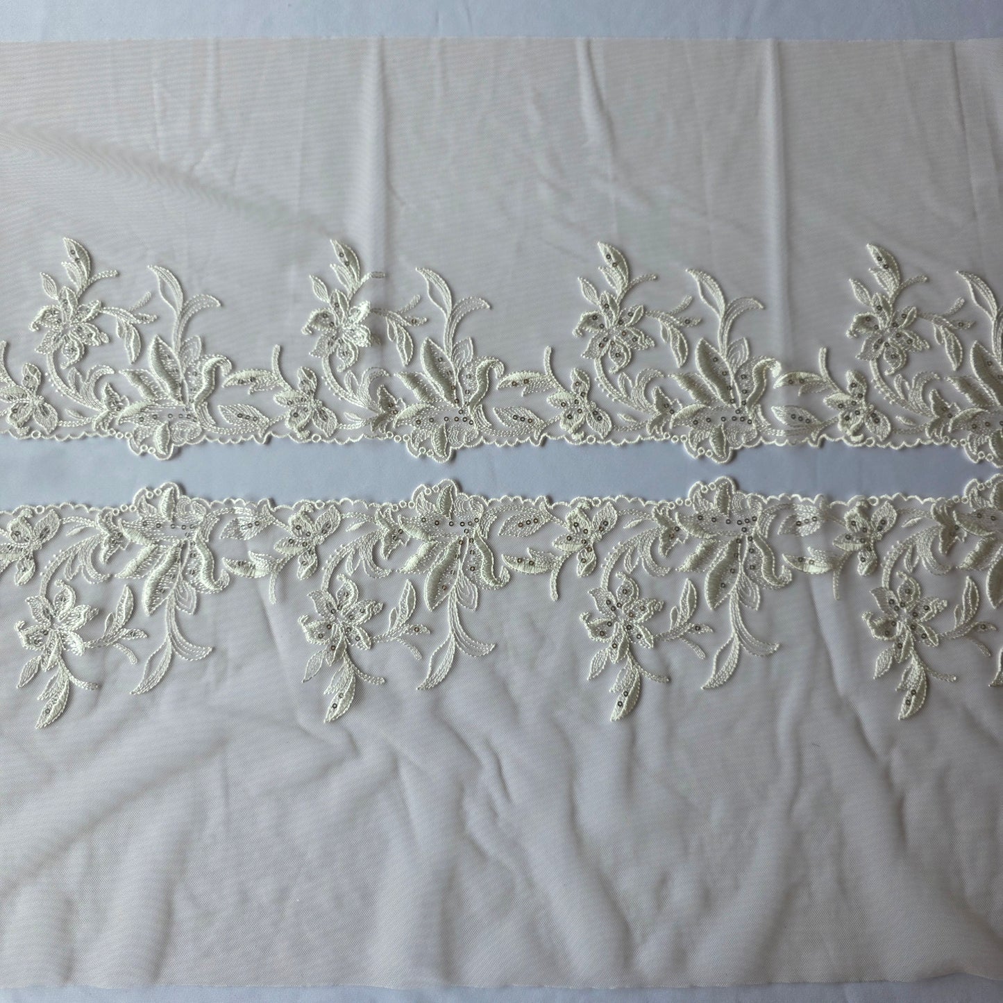 2025-113 peach kleurig tule kant met geborduurde witte lelies voorzien van zilverkleurige pailletten