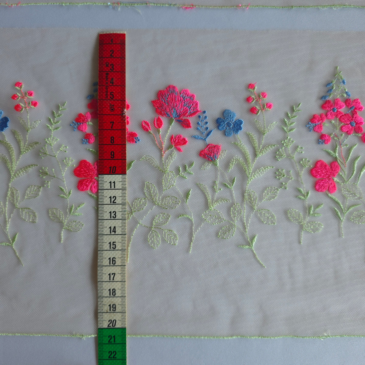 2026-112 peach kleurig tule kant voorzien van veldbloemen in lichtgroen, neon roze en korenbloem blauw