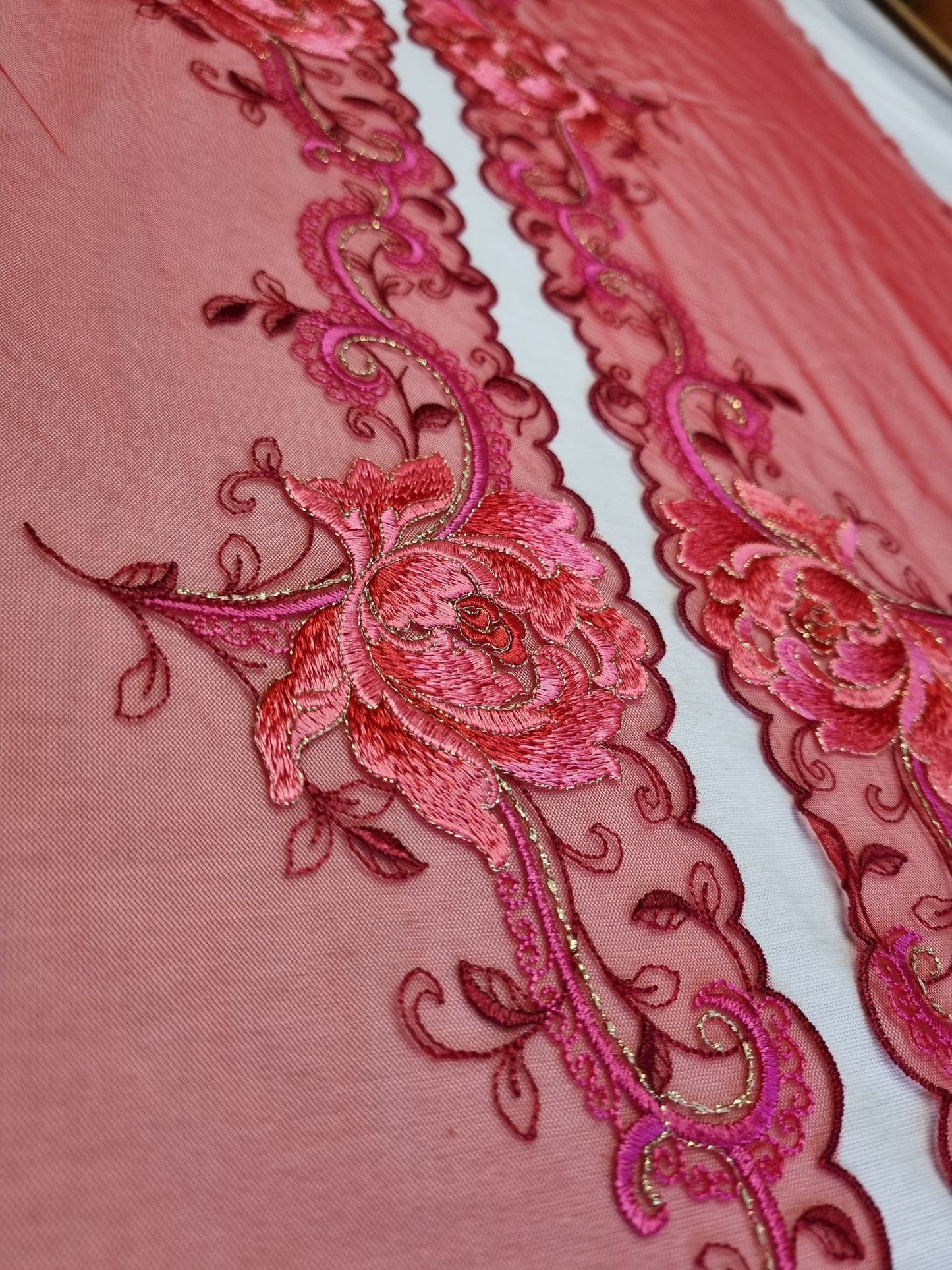 Rood tule kant met roze geborduurde bloemen.