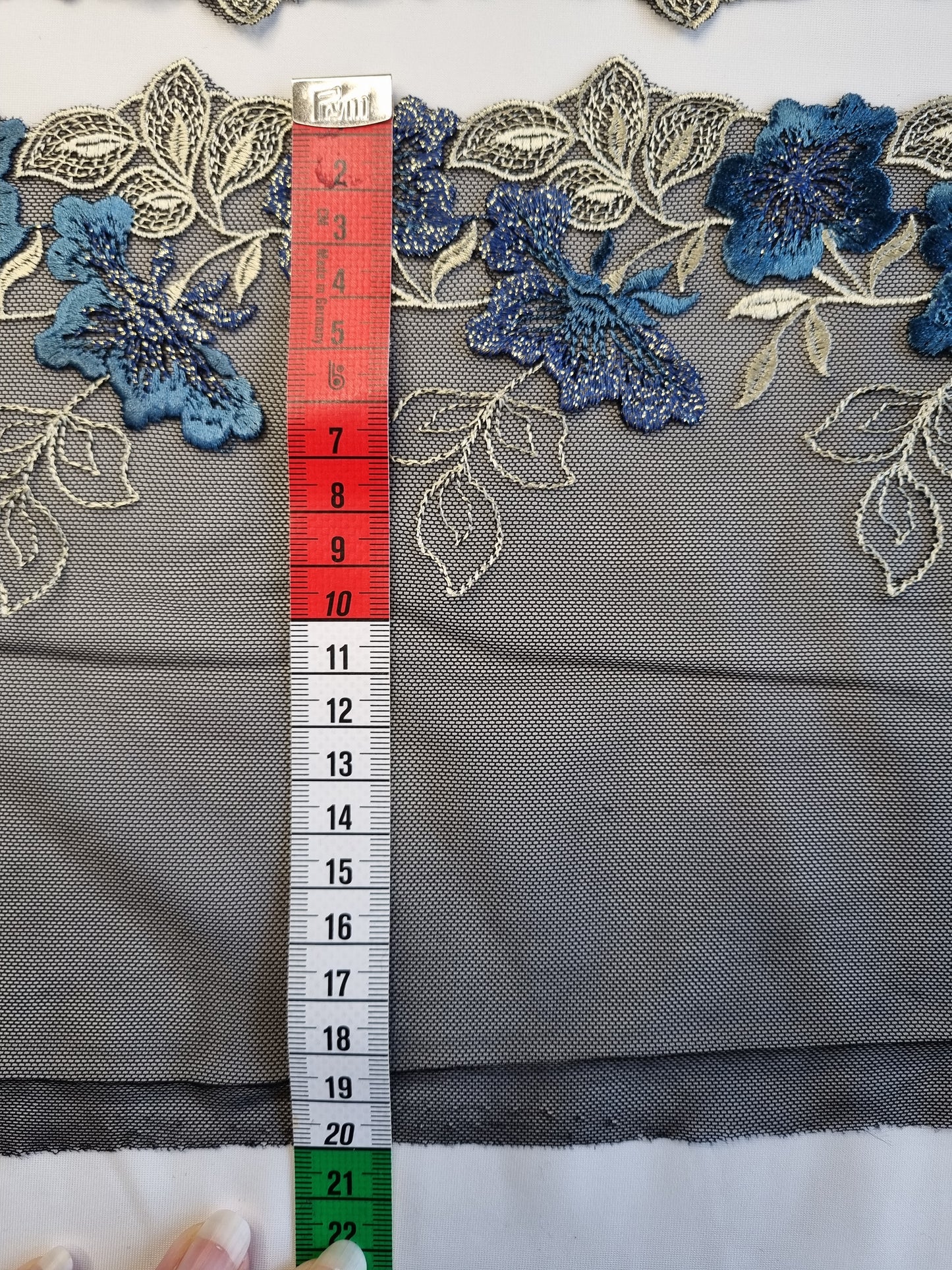 Zwart tule kant met blauwe geborduurde bloemen en goudkleurige lurex draad.
