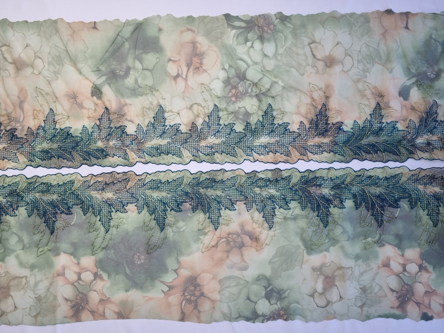 Groen tule kant met geborduurde abstracte blaadjes.