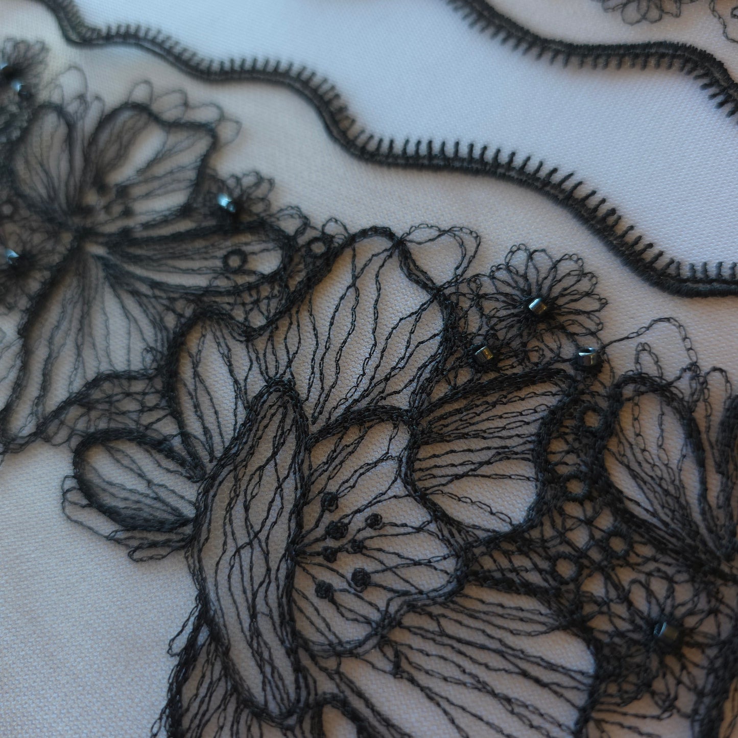 2025-90 beige tule kant met geborduurde bloemen in zwarte lineart voorzien van glaskraaltjes