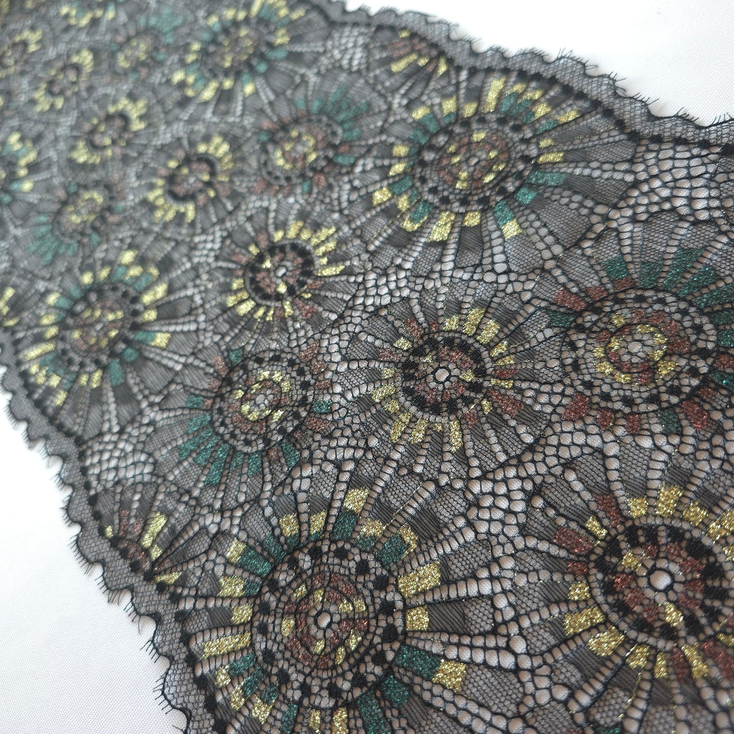 2025-101 zwart stretchkant met abstract vuurwerk voorzien van lurexgaren in goud, groen en bruin
