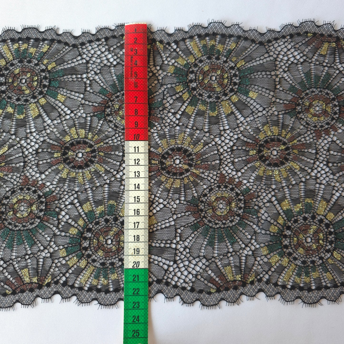 2025-101 zwart stretchkant met abstract vuurwerk voorzien van lurexgaren in goud, groen en bruin