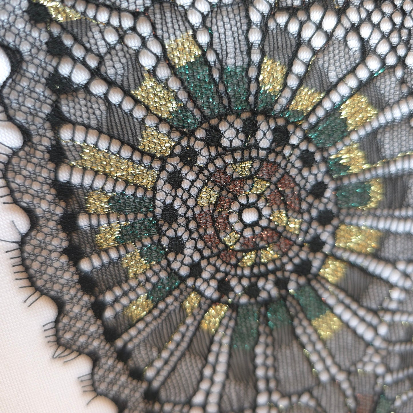 2025-101 zwart stretchkant met abstract vuurwerk voorzien van lurexgaren in goud, groen en bruin