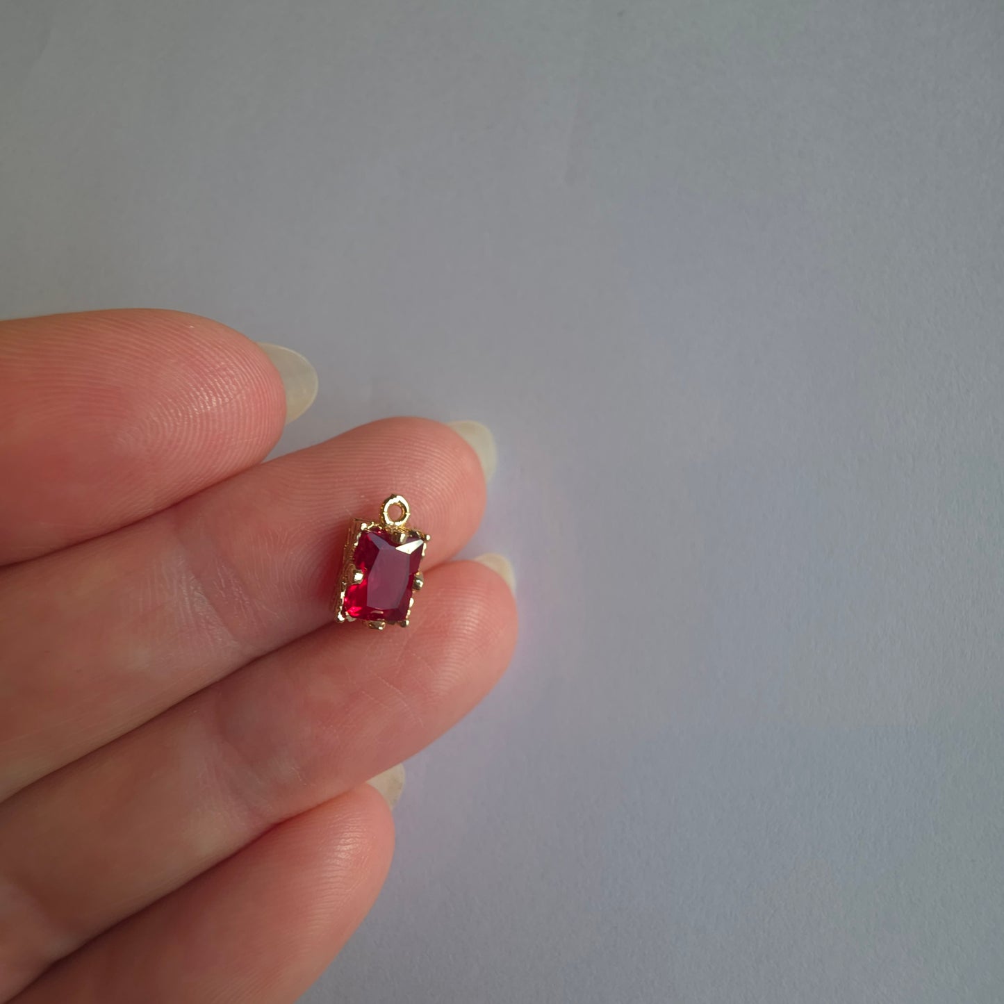 goudkleurig bedeltje ingezet met rechthoekig rode zirkoon