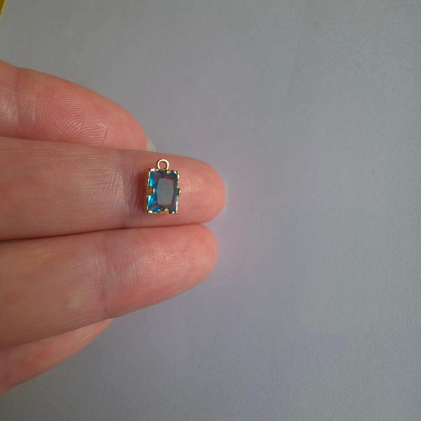 goudkleurig bedeltje ingezet met rechthoekig turquoise zirkoon