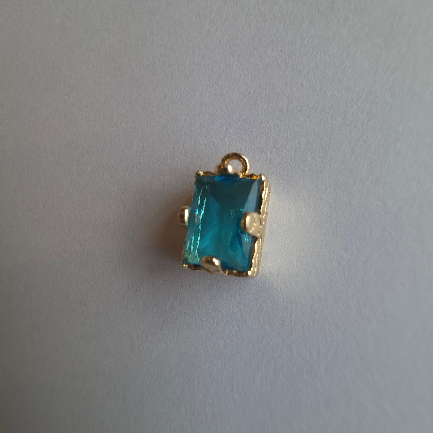 goudkleurig bedeltje ingezet met rechthoekig turquoise zirkoon