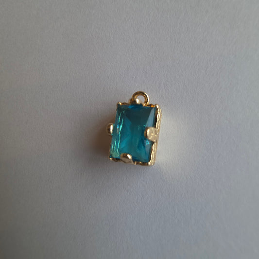 goudkleurig bedeltje ingezet met rechthoekig turquoise zirkoon