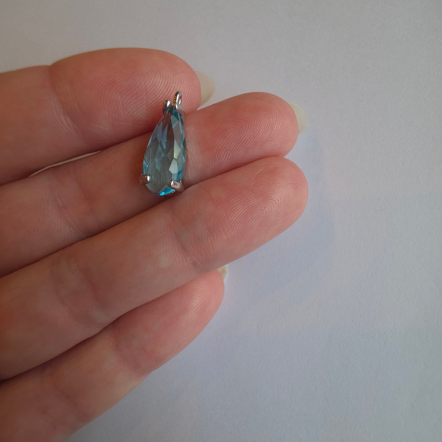 zilverkleurig bedeltje met druppelvormige zirkoon in lichtblauw