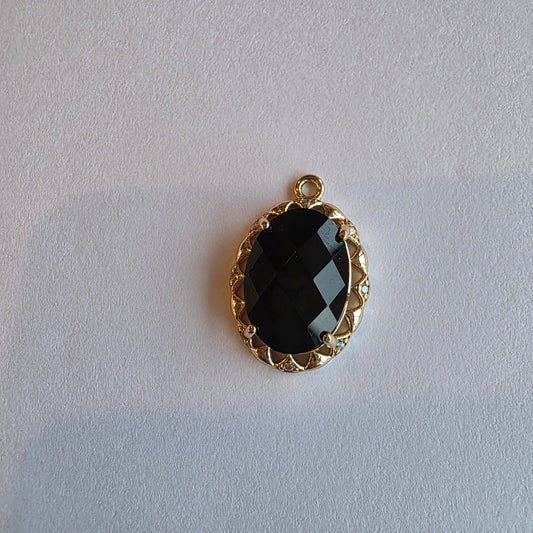 goud kleurig bedeltje met zwart zirkoon voorzien van rand die ingezet is met witte zirkoontjes