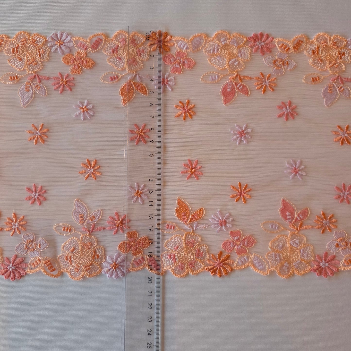 2026-13 lichtroze geborduurd stretchkant met bloemetjes in roze, peach, licht oranje en lila