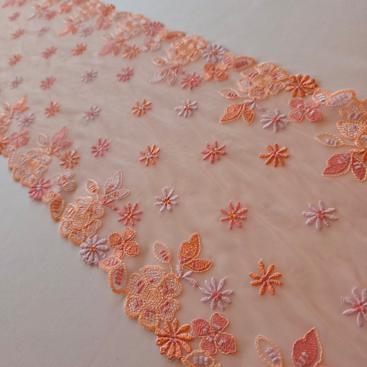 2026-13 lichtroze geborduurd stretchkant met bloemetjes in roze, peach, licht oranje en lila