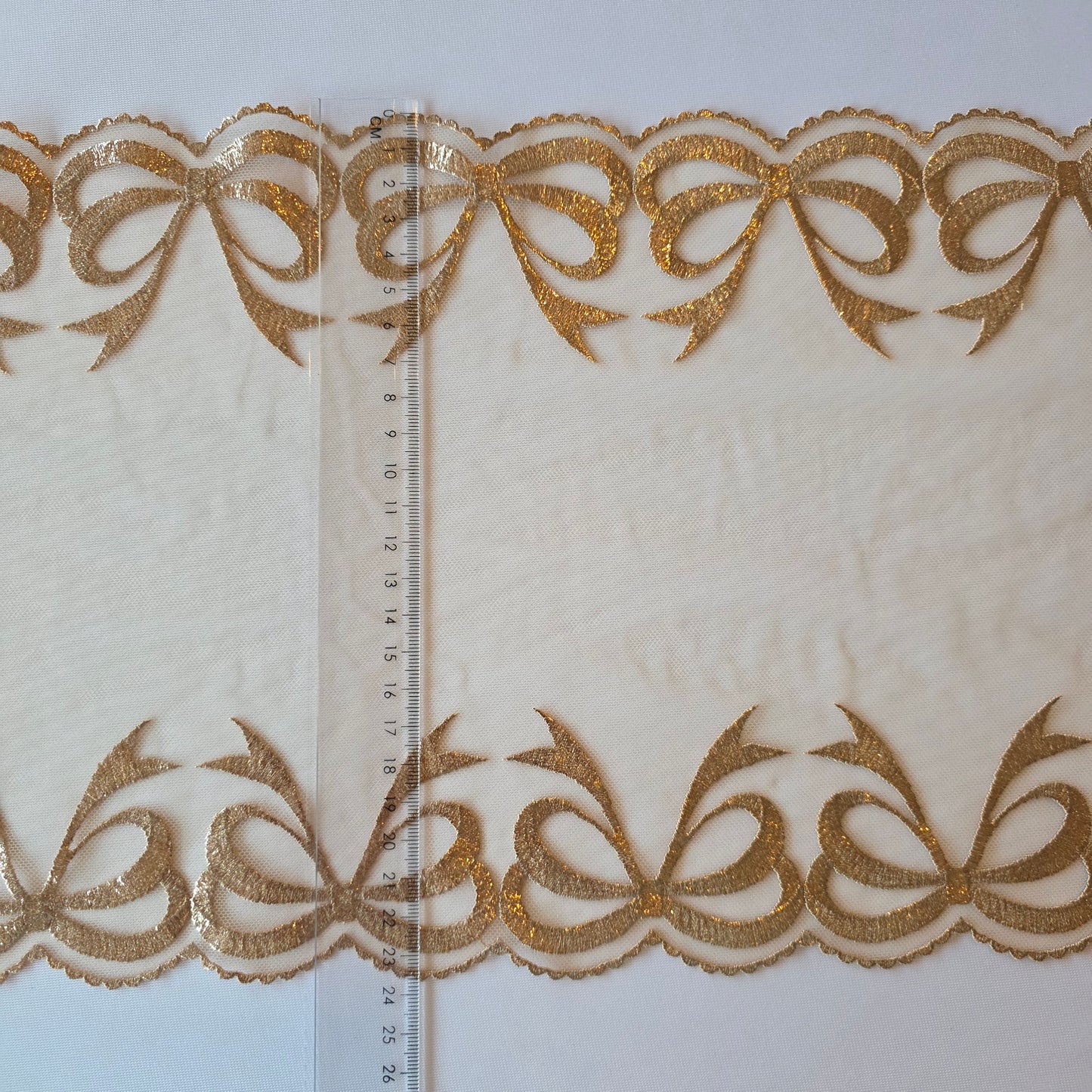 2026-25 Latte kleurig tule kant met geborduurde strikken, voorzien van goudkleurige folieprint