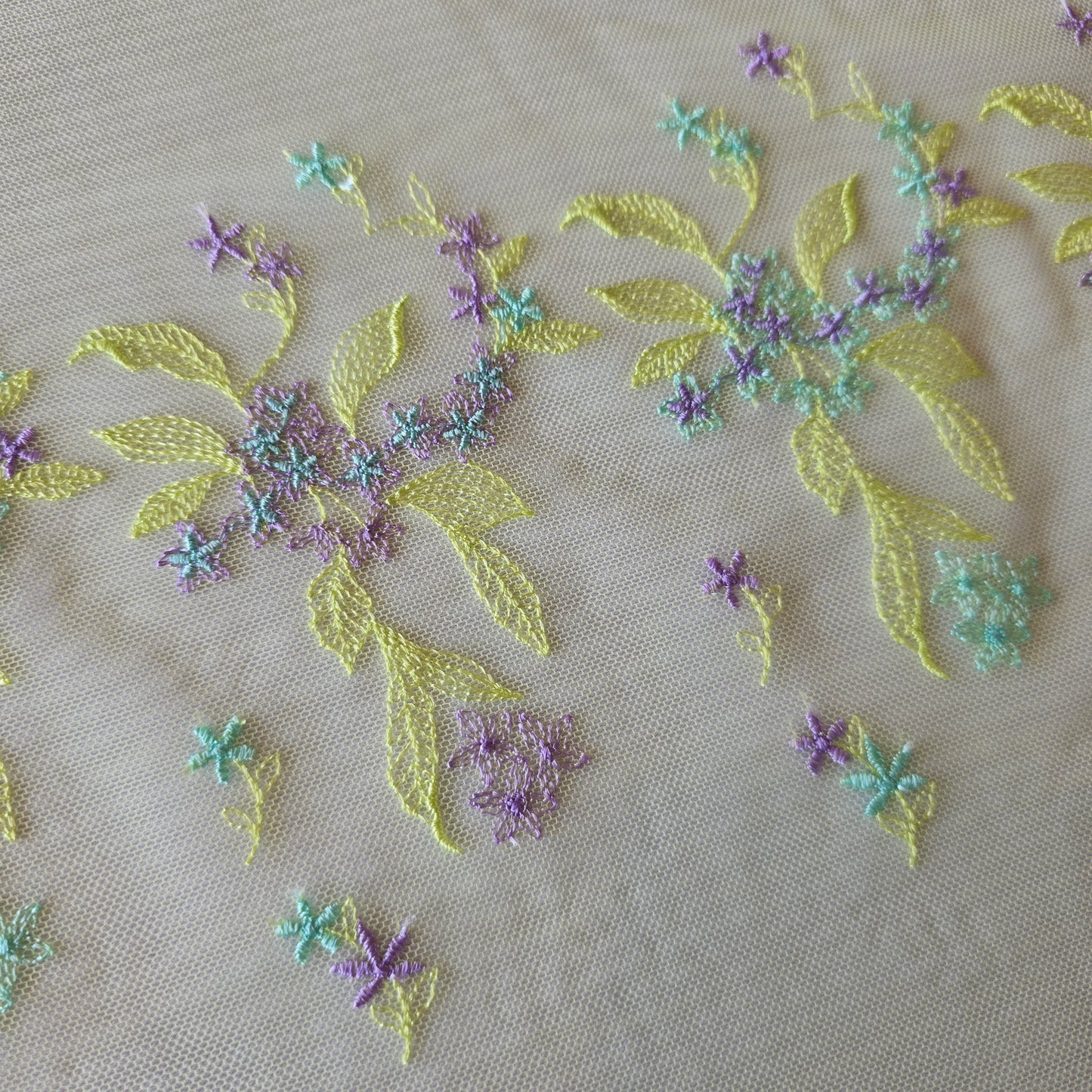 2026-32 licht chartreuse tule kant met in chartreuse, lichtblauw en lila geborduurde bloemetjes