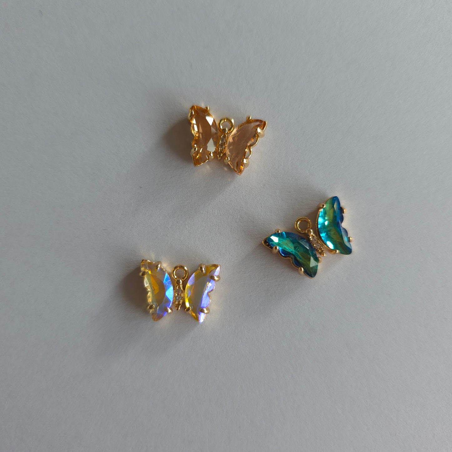 Goudkleurige vlinder-bedeltjes met lichtroze zirconia + ingelegde zirconiatjes in het lijfje in verschillende kleuren