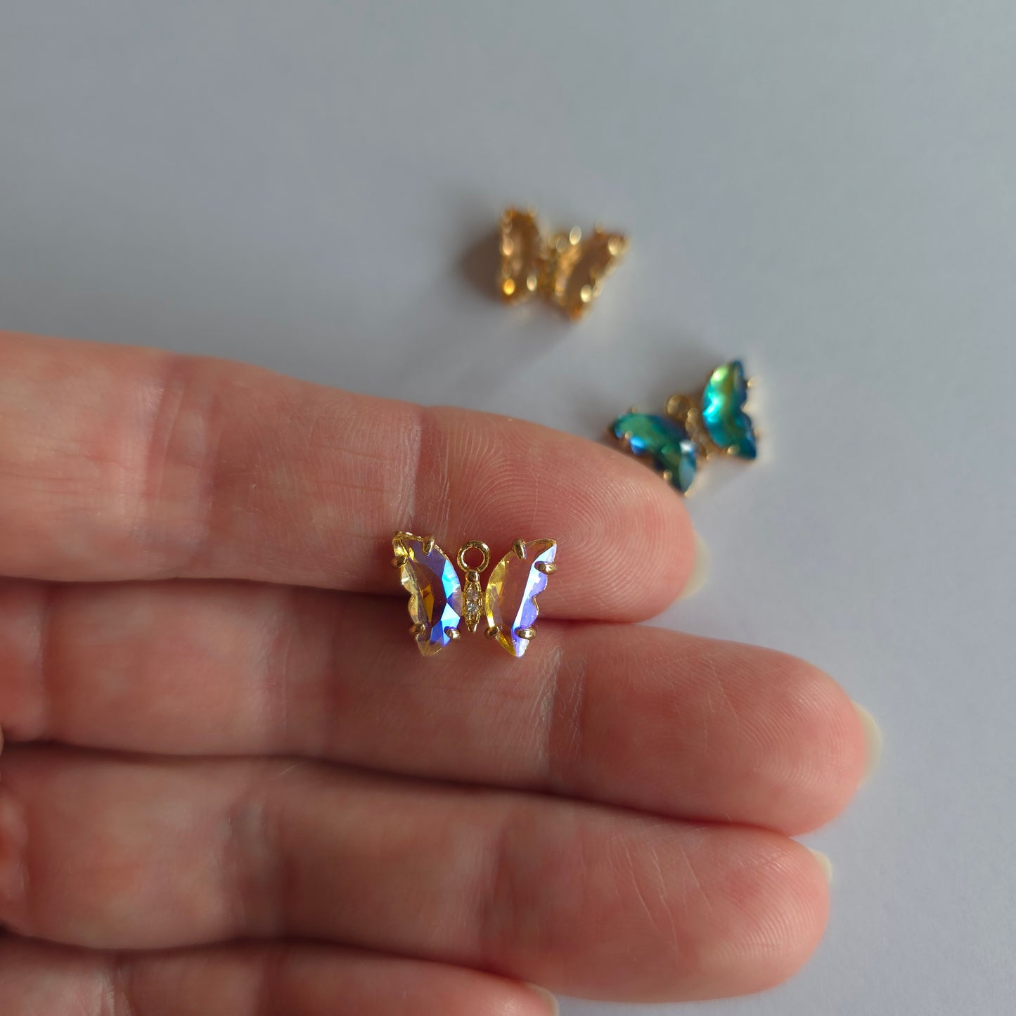 Goudkleurige vlinder-bedeltjes met lichtroze zirconia + ingelegde zirconiatjes in het lijfje in verschillende kleuren