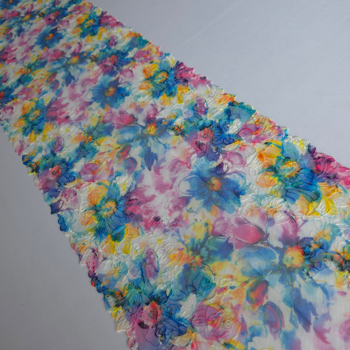 2026-106 wit tule kant met bloemen borduursel voorzien van print in blauw, fuchsia, paars en geel
