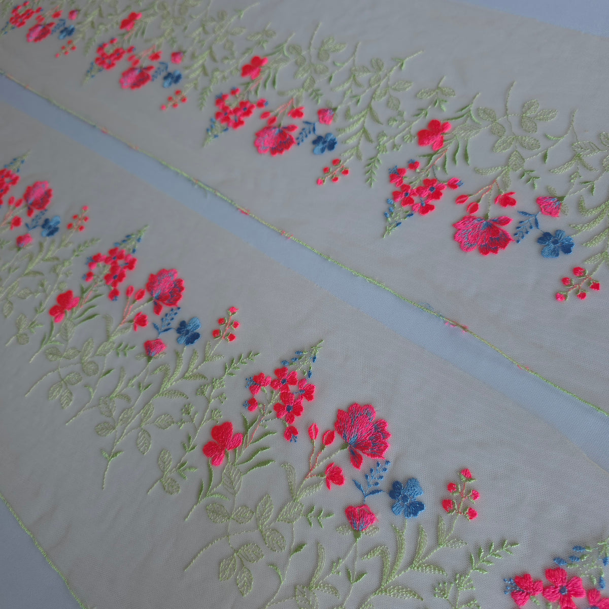 2026-112 peach kleurig tule kant voorzien van veldbloemen in lichtgroen, neon roze en korenbloem blauw