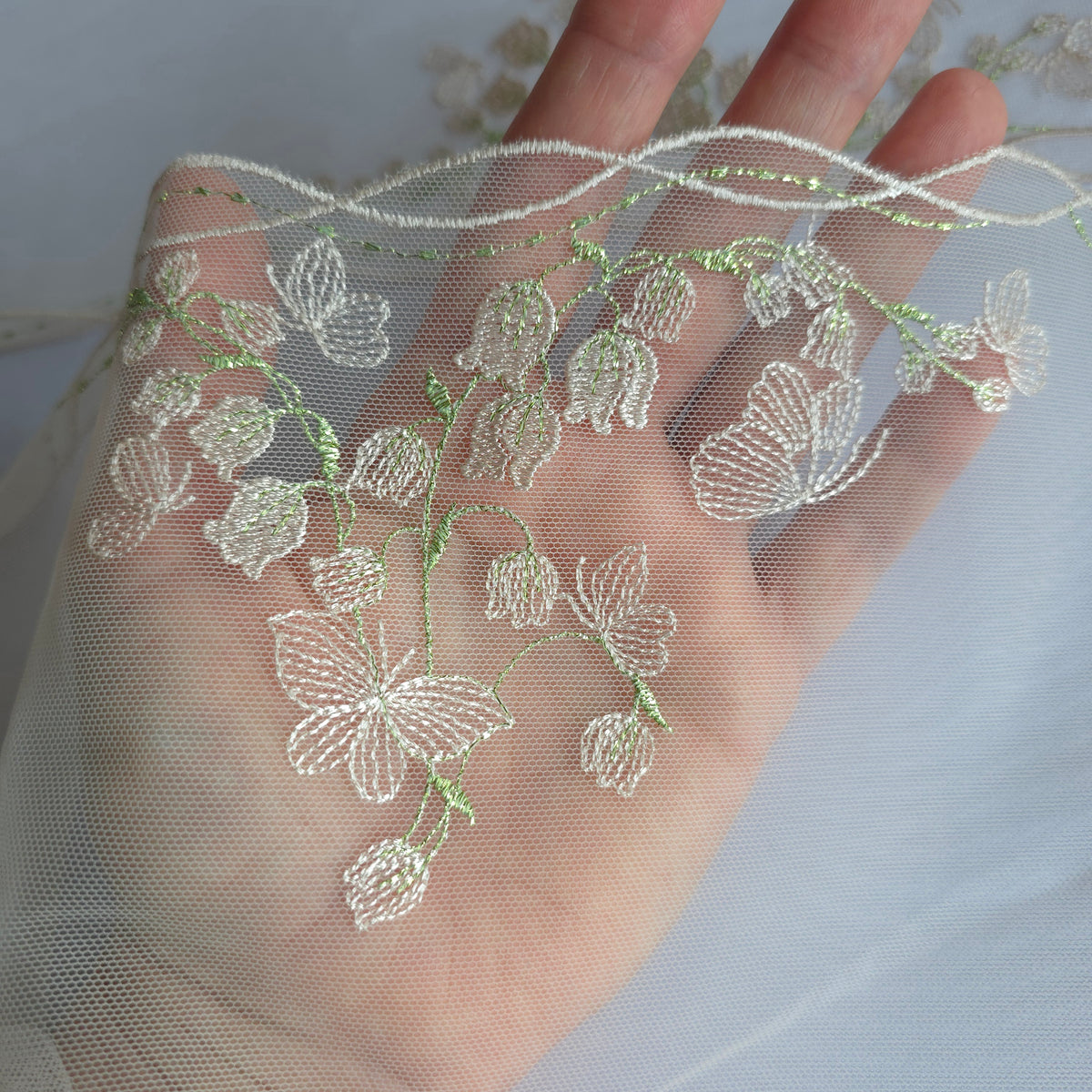 2026-115 heel lichtroze tulekant met geborduurde lelietjes-van-dalen en vlinders voorzien van lichtgroen lurex draad